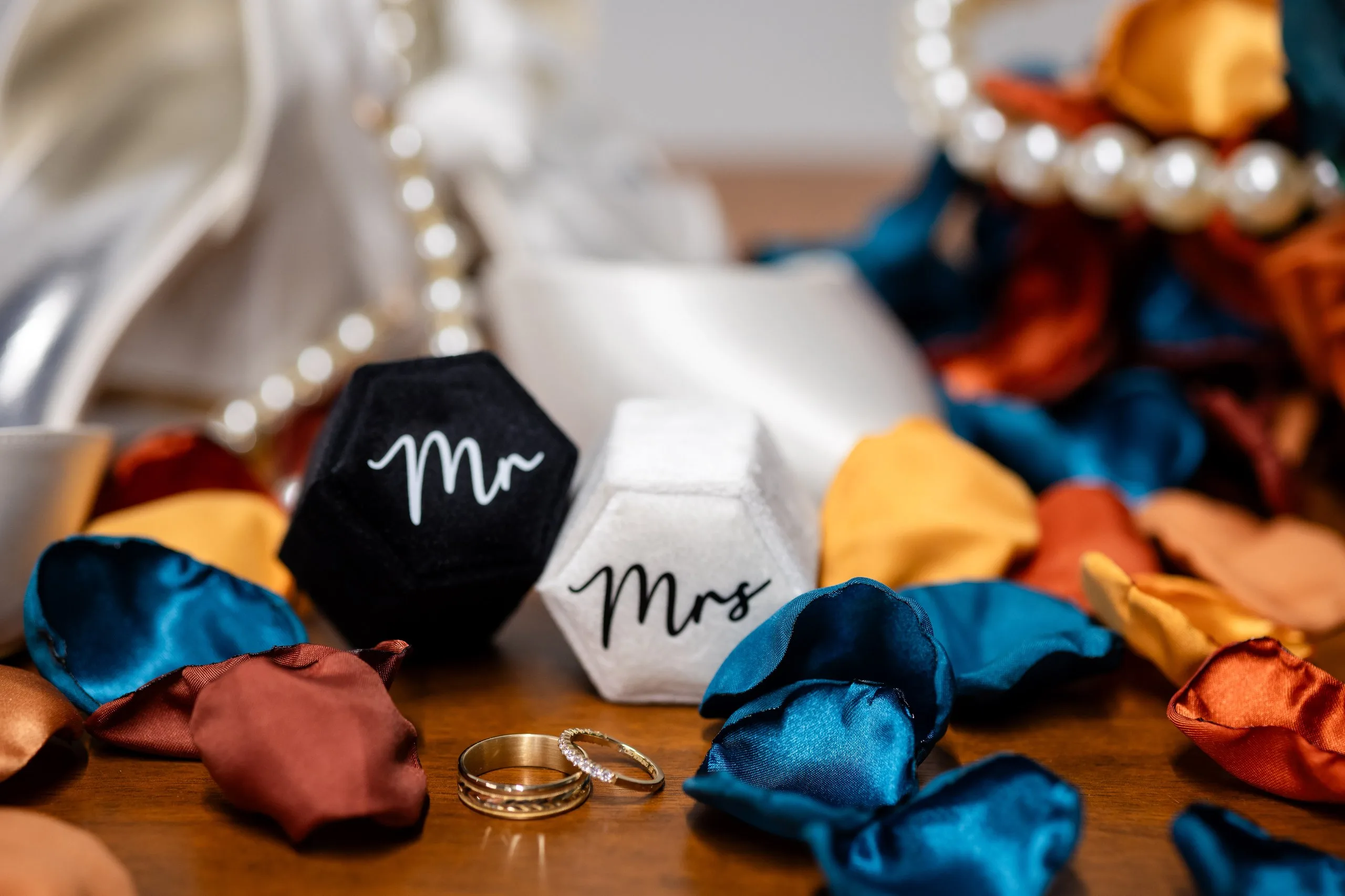 Mr and Mrs signs with wedding rings on blue and orange petals