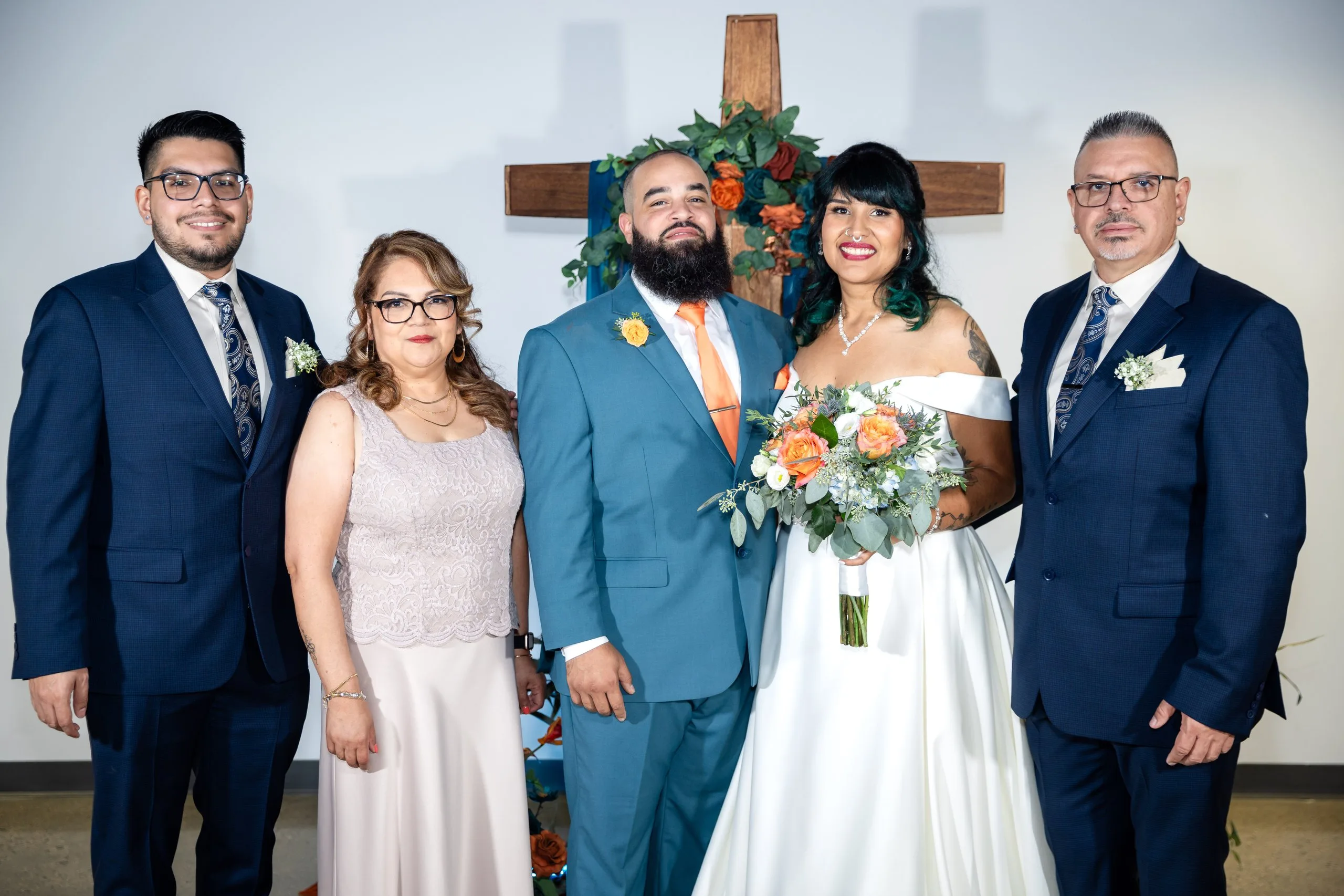 Bride and groom with their parents at the ceremony arch